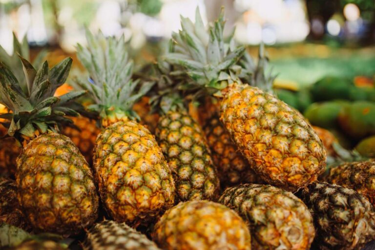 A store display of ripe pineapples stacked in a produce section