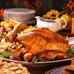 A delicious roasted turkey on a festive Thanksgiving table with all the fixings. Candles and flowers for ambiance.