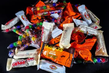 A vibrant pile of assorted Halloween candies, including chocolate bars and sweets
