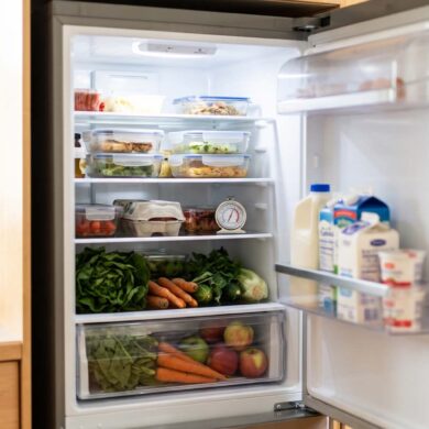 Open refrigerator with a thermometer, leftovers in shallow containers and produce stored unwashed