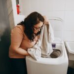 A woman in here laundry room inspecting freshly washed laundry