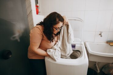 A woman in here laundry room inspecting freshly washed laundry