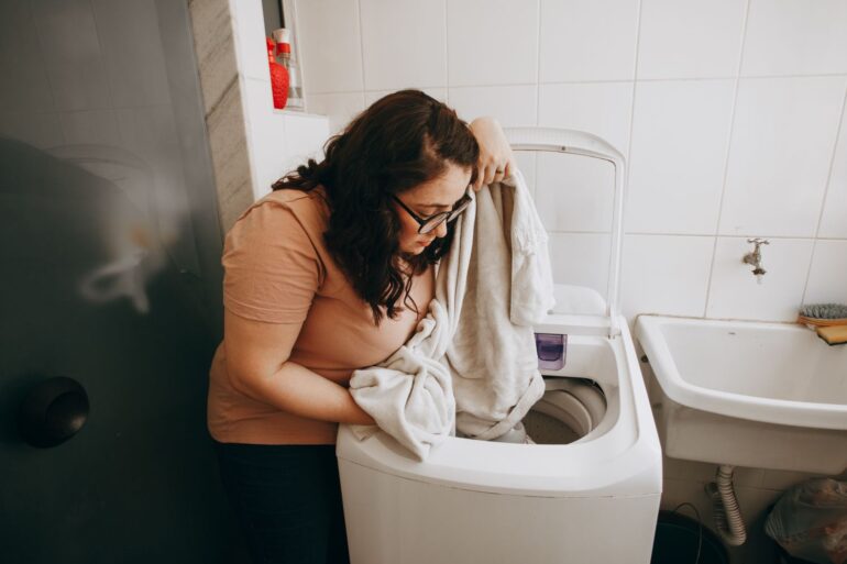 A woman in here laundry room inspecting freshly washed laundry