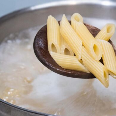 a bot of boiling pasta water with a spoonful of penne