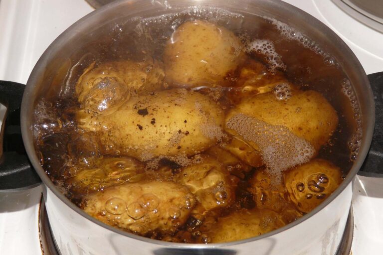 A large pot filled with water and potatoes coming to boil