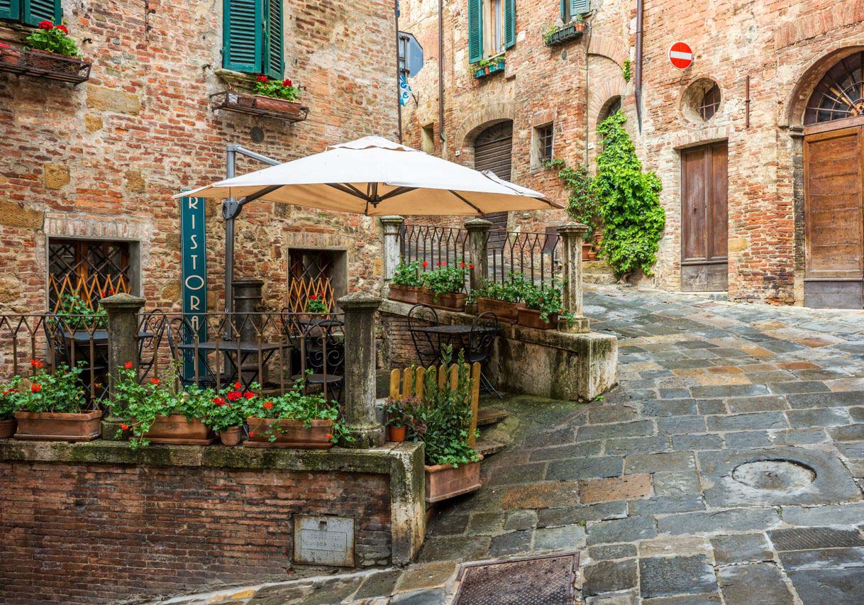 Charming view of a medieval alleyway in Montepulciano, Tuscany - Italy, featuring rustic buildings and a café.