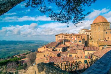 Panoramic view of Volterra's historic architecture and scenic landscape under a clear sky