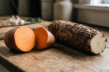 a close up side by side shot of a sweet potato and a yam on a rustic table