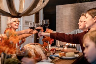 A family celebrates around a Thanksgiving table toasting wine