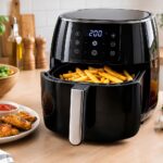 A modern air fryer on a clean kitchen countertop, surrounded by fresh vegetables, crispy fries, grilled chicken, herbs, spices, and cooking ingredients.