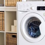 an up close shot of a washing machine in a laundry room with the door closed and wet clothes inside