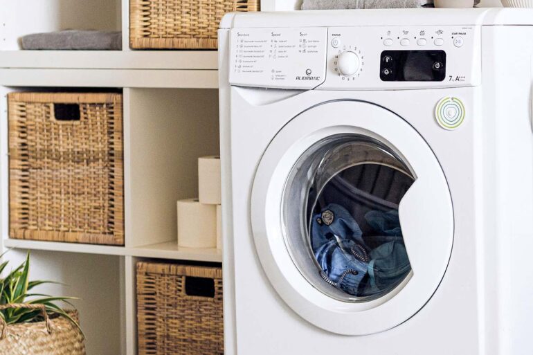 an up close shot of a washing machine in a laundry room with the door closed and wet clothes inside