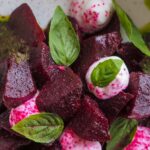 a close up of a fresh beet salad with basil leaves and cheese