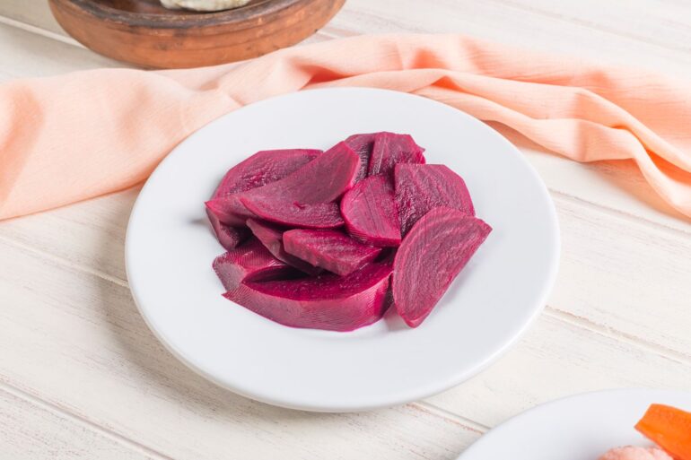 a plate of sliced pickled beets on a wooden table