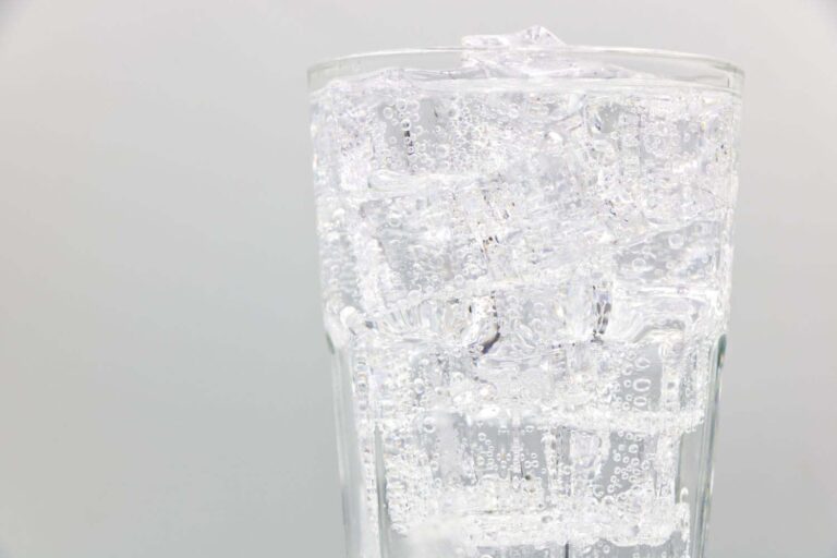 an up close shot of a glass of bubbly club soda and ice