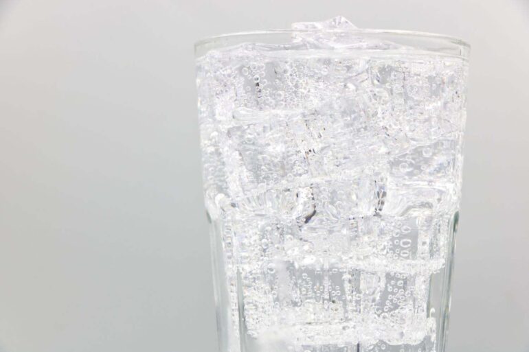 an up close shot of a glass of bubbly club soda and ice