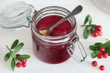 A jar of cranberry sauce with a spoon