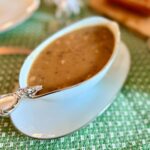 a porcelain gravy boat filled with homemade gravy on a set table