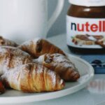 croissants and coffee with Nutella jar on a table