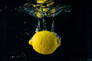 close up of a whole lemon being dropped into water