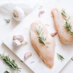 Top view of raw chicken breasts with rosemary and garlic